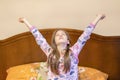 A nice child girl enjoys sunny morning. Good morning at home. Child girl wakes up from sleep. Little girl stretching in bed at Royalty Free Stock Photo