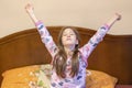 A nice child girl enjoys sunny morning. Good morning at home. Child girl wakes up from sleep. Little girl stretching in bed at Royalty Free Stock Photo