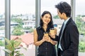 Nice coffee break, business woman drinking an espresso during a small talk with a young colleague while standing in office Royalty Free Stock Photo