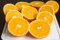 Nice composition of fresh oranges cut in half on a white cutting board on the dark kitchen table. Royalty Free Stock Photo