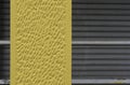 Nice concrete background toned yellow against closed gray shutters - Wall surface texture - Grunge bright illuminating color