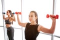 Nice and confident young women exercising with dumbbells at window. Asian model stand in front and look forward