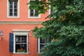 Nice, cozy house of coral color, windows with shutters, flowerpots with flowers on the windowsill, a lantern on the wall