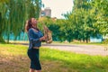 Pretty young woman with red hair in a blue sweater and black skirt plays on a yellow saxophone in a city green park