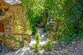 Nice driveway to an old stone house with fences and wooden stools and decorated with lots of greenery