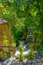 Nice driveway to an old stone house with fences and wooden stools and decorated with lots of greenery. Selective focus