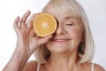 Nice elated woman putting an orange half to her eye