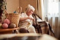 Lovely old woman knitting and using laptop at home Royalty Free Stock Photo