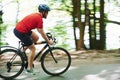 Nice feeling. Cyclist on a bike is on the asphalt road in the forest at sunny day