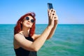 Red-haired woman takes selfie on smartphone camera. Royalty Free Stock Photo