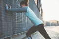 Nice and fit woman doing warming exercise on the street, safety stretching before workout