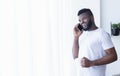 Cheerful black man talking on mobile phone, looking at window with coffee Royalty Free Stock Photo