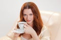 Nice girl in beige home dressing gown with a cup of coffee