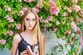 Nice girl in glasses with white hair on a background of a flowering rose bush is reading a book Royalty Free Stock Photo