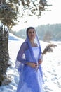 Vertical portrait against the background of the winter landscape of a beautiful young brunette in a long white dress and a Royalty Free Stock Photo