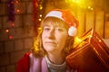 Nice girl in a red dress and hat of Santa with big red gift box in room decorated for Christmas. Woman in beautirul Royalty Free Stock Photo