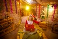 Nice girl in a red dress and hat of Santa with big red gift box in room decorated for Christmas. Woman in beautirul Royalty Free Stock Photo