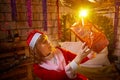 Nice girl in a red dress and hat of Santa with big red gift box in room decorated for Christmas. Woman in beautirul Royalty Free Stock Photo