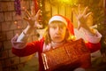 Nice girl in a red dress and hat of Santa with big red gift box in room decorated for Christmas. Woman in beautirul Royalty Free Stock Photo