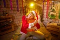 Nice girl in a red dress and hat of Santa with big red gift box in room decorated for Christmas. Woman in beautirul studio during Royalty Free Stock Photo