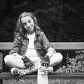 Nice girl, teenager, sitting on a bench with a skateboard. Black and white photo. Healthy lifestyle. Sport