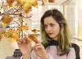 Nice girl touching artificial autumn tree at mall