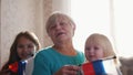 A nice girls and their grandmother enjoy sunny morning. Good time at home. Flag of Russia in hands of granny