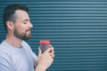 Nice and happy person is holding cup of coffee witht both hands. He is smiling. Guy is keeping eyes closed. Isolated on Royalty Free Stock Photo