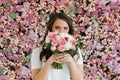 Nice healthy woman smiling and holding colorful pink color flower bouquet on floral spring or summer background, studio fashion Royalty Free Stock Photo