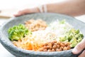 Nice image of a woman serving fresh salad in a buddha bowl.