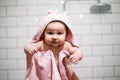 Nice infant is looking on camera. She is serious. It is holded by adult`s hands. Baby is covered with pink blanket. Isolated on Royalty Free Stock Photo