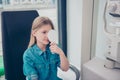 Nice little blond girl in jeans casual outfit at the ophthalmologist on consultation is covering her eye for checking her visual Royalty Free Stock Photo