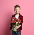 Nice little boy kid in blue jeans and red shirt gives a big bouquet of spring flowers for a Mothers day or other holiday