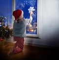 Little boy with snowflake decorating window Royalty Free Stock Photo