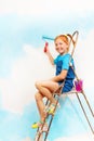 Nice little girl in blue sits on a ledge