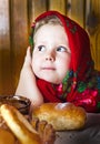 Little girl in Russian shawl with rolls and honey