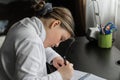 Nice little girl sitting behind the table and doing home work in her room at morning time Royalty Free Stock Photo