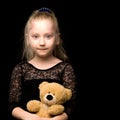 Little girl with a teddy bear on a black background. Royalty Free Stock Photo