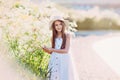 Nice little girl in white dress and hat walking near giant flowers Royalty Free Stock Photo