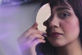 nice-looking Caucasian girl holding a half disk near at her face and looking at the camera confidently, closeup shot