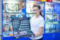 Nice looking girl saleswoman offers set of tools in an auto parts store. Ready to repair the car