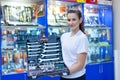 Nice looking girl saleswoman offers set of tools in an auto parts store. Ready to repair the car