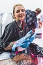 nice-looking tattooist girl working in the studio and smiling to the camera, medium vertical shot