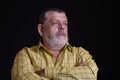 Portrait of a thoughtful Caucasian, bearded senior man in yellow shirt