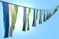 nice many Sierra Leone flags or banners hanging diagonal on rope on blue sky background with bokeh - any occasion flag 3d