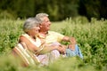 Portrait of nice mature couple sitting on green grass in summer park Royalty Free Stock Photo