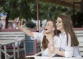 Nice meeting at a cafe. Summer holydays. Two girls make a selfie Royalty Free Stock Photo