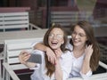 Nice meeting at a cafe. Summer holydays. Two girls make a selfie while sitting in summer cafe. Royalty Free Stock Photo