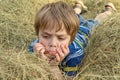 Nice offended kid with insulted expression face, lies on the hay (concept of children\'s emotions)