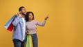 Nice Offer. Excited young black spouses with bright shopping bags pointing aside Royalty Free Stock Photo